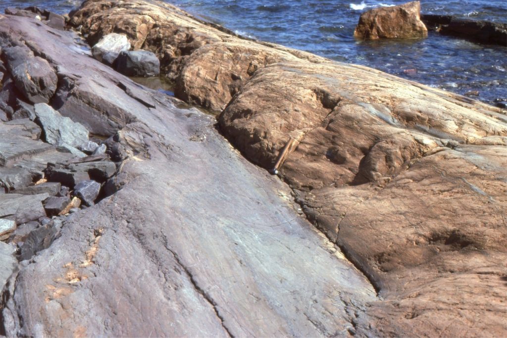 Mixed, crossbedded siliciclastic-grainstone facies of intertidal persuasion, overlain by pisolitic dolostone. The contact appears abrupt but in fact is diffuse over several centimeters, and represents a ‘weathering-diagenetic front’. Hammer at center.