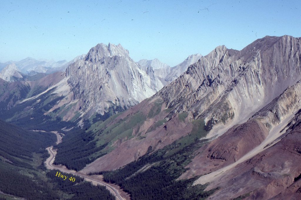 Part of the Alberta Front Ranges fold -thrust belt north of Highwood Pass. Sawtooth-like Lower Paleozoic carbonates are exposed as flatirons in the hanging wall of a thrust immediately east of Lewis Thrust. Late Jurassic – Early Cretaceous foredeep deposits in the valley floor (mostly covered) were involved in the deformation as the orogenic load migrated eastward. Orogenic transport to the right.