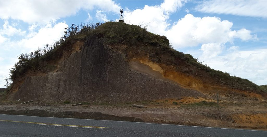 Road cut through a Mamaku Ignimbrite tor (Hwy 5, west of Rotorua). The eroded top of the Ignimbrite is draped by younger airfall tephra. See Google Earth image above for location. Taupo Volcanic Zone, New Zealand.