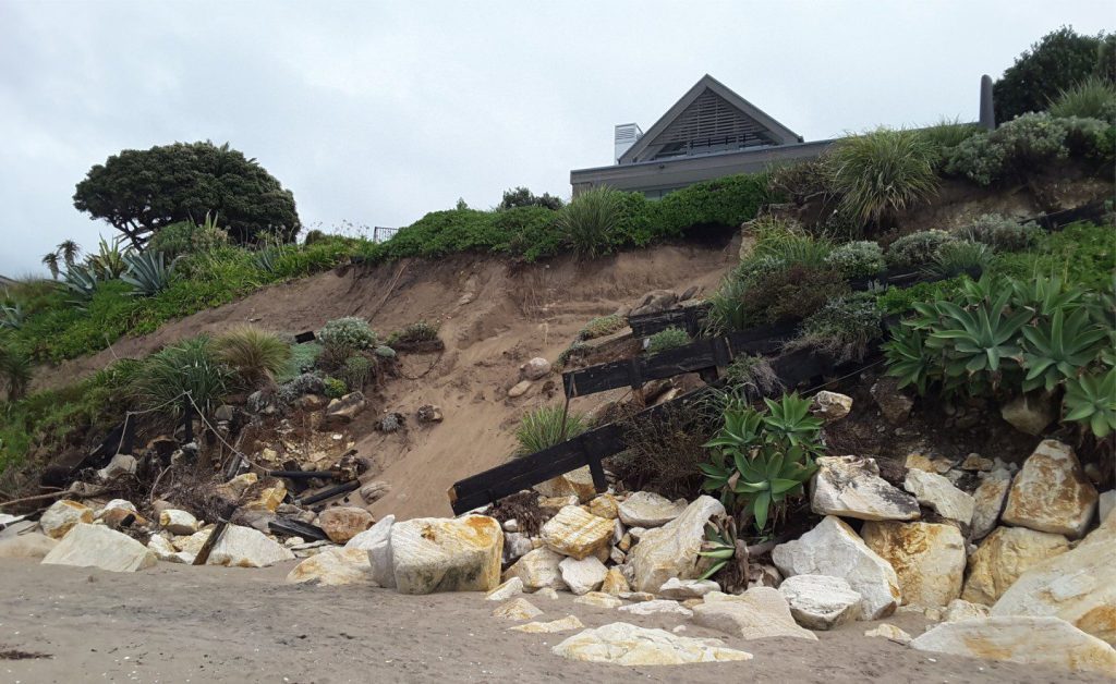 Erosion of unconsolidated coastal dune sands by storm surges driven by cyclone Gabrielle damaged building foundations and beach access ways. The artificial carapace of boulders and blocks, intended as a coastal defense, was easily dismantled by wave surges that coincided with high tide. The storm was a category 3 tropical cyclone that tracked the east coast of Aotearoa New Zealand's North Island in February 2023.